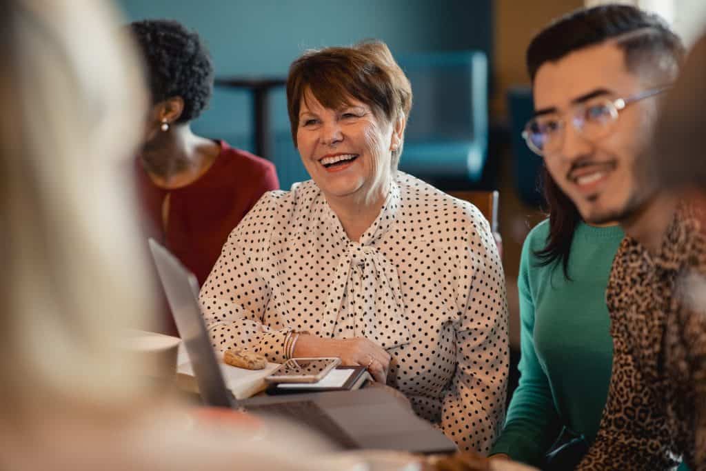 Woman laughing and sitting alongside a group around her