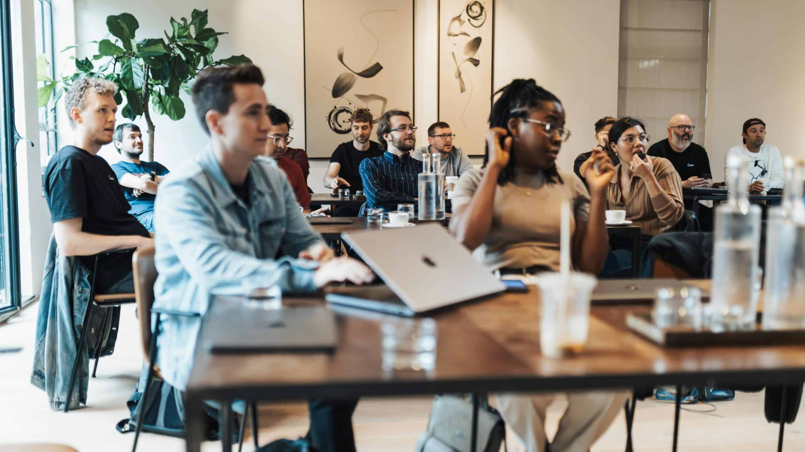 group of people casually dressed at an informal meeting event. They are listening to the speaker at the front of the room.jpg