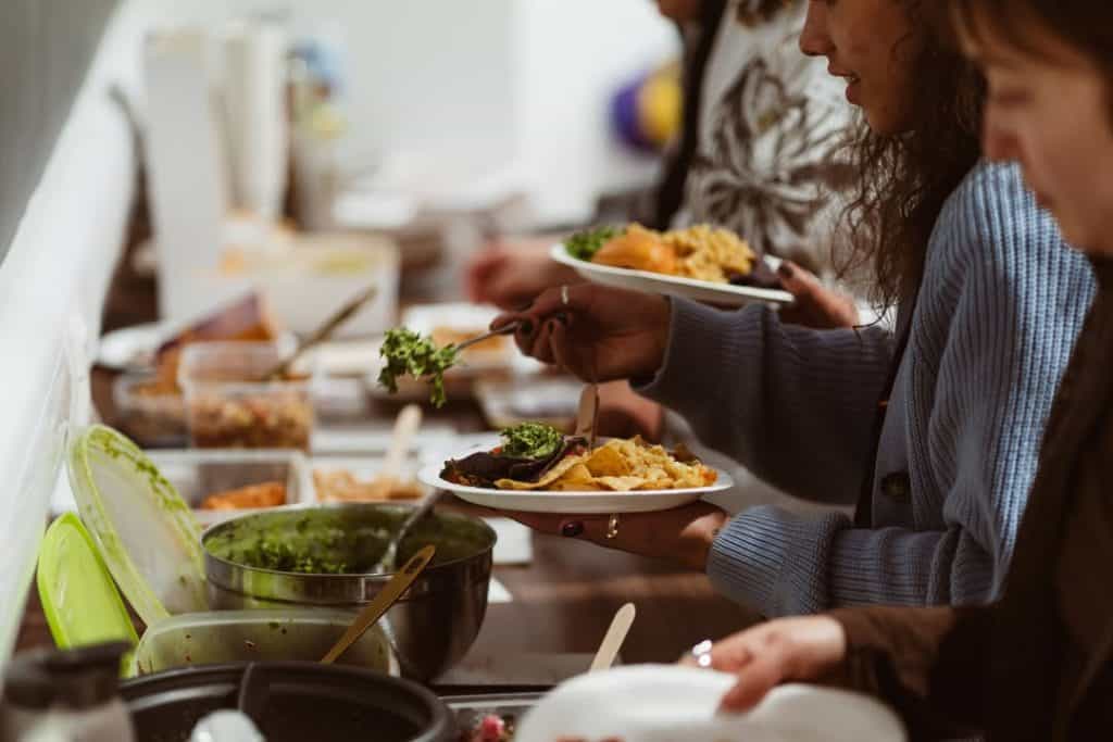 Photo of people putting food on their plates at a pot luck