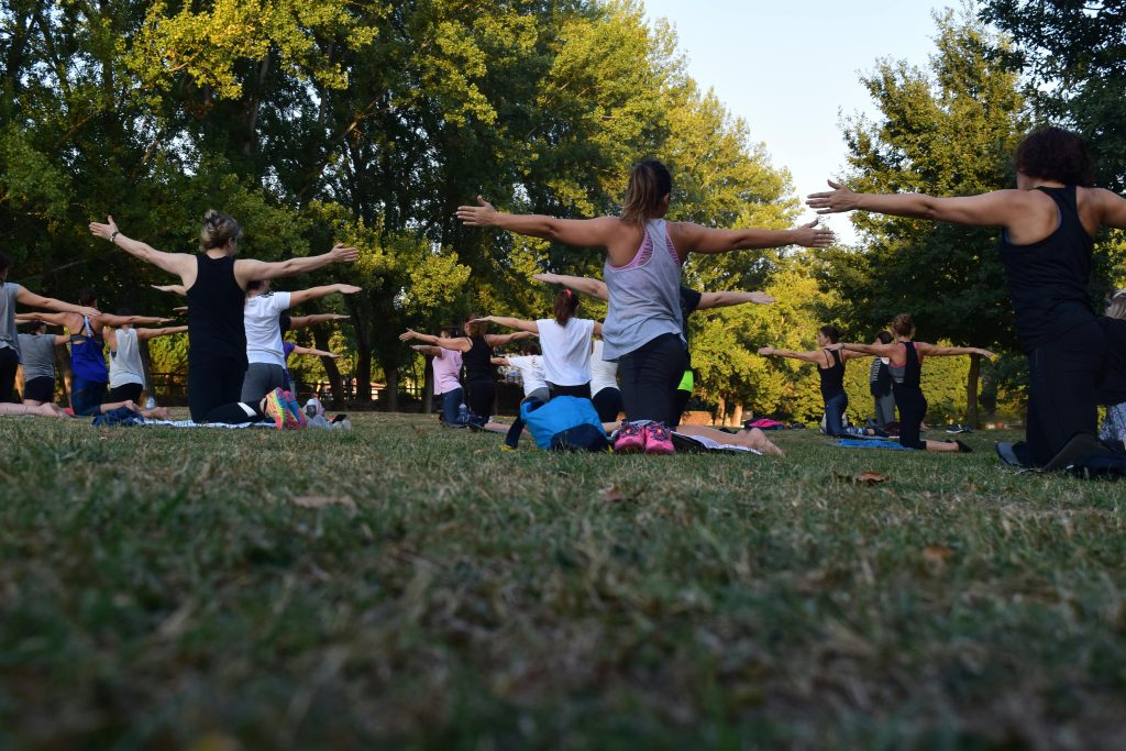 group of women doing yoga outdoors in a park