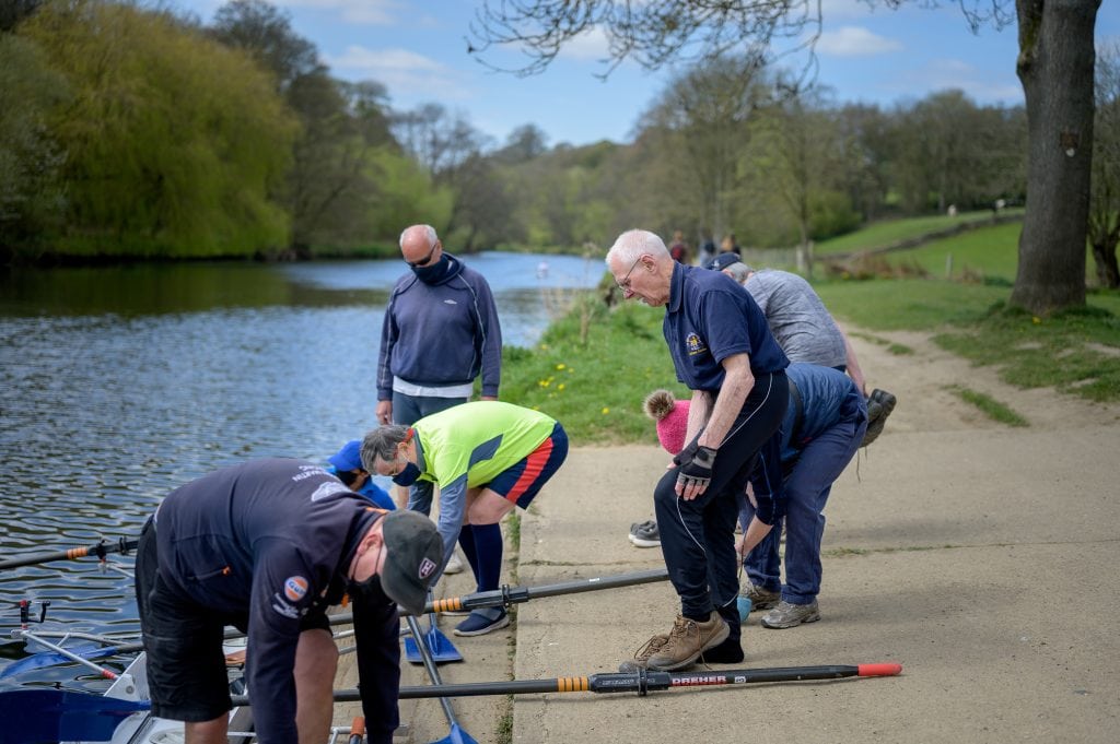 older people preparing boats to take onto a river
