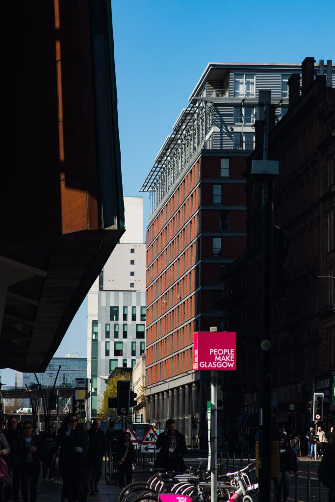 New office from across the street with people make glasgow sign in foreground
