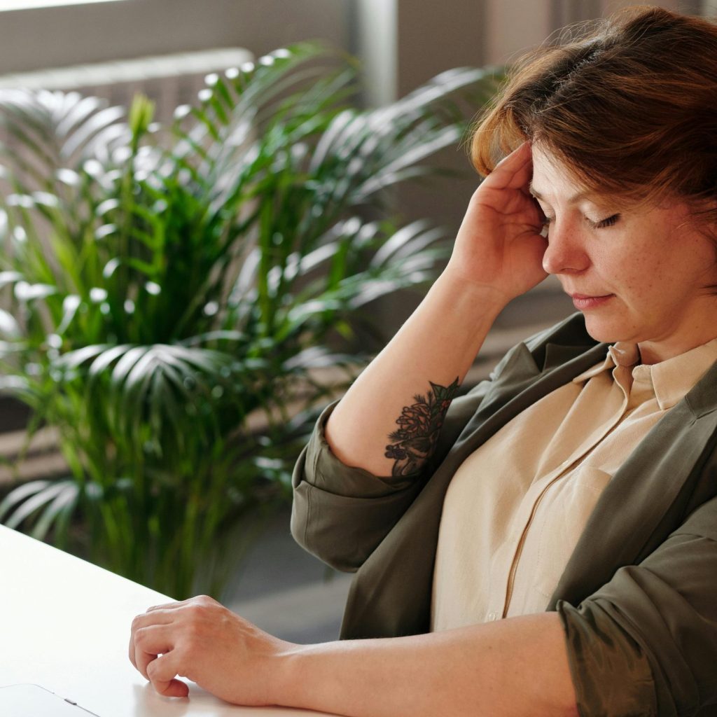 woman experiencing a sore head sitting at a desk